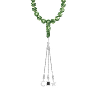 Close-up of a person holding a green gemstone tasbih with gold-plated tassels, featuring an embedded nano chip with the entire Quran.