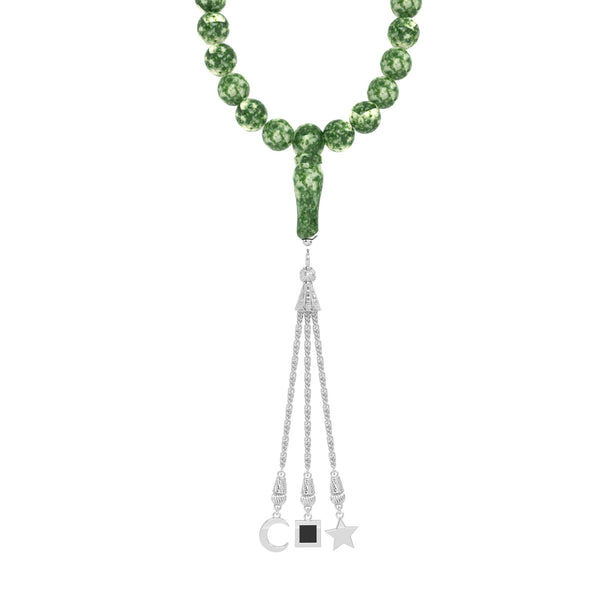 Close-up of a person holding a green gemstone tasbih with gold-plated tassels, featuring an embedded nano chip with the entire Quran.