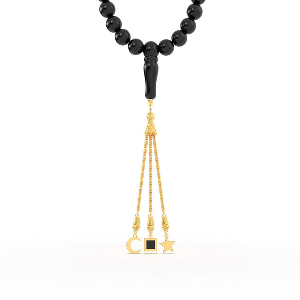 Gold tasbih with black beads and a gold tassel featuring three pendants, with the central square pendant containing a black nano chip inscribed with the entire Quran, displayed on a white background.