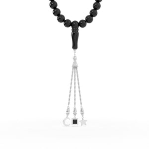 Silver tasbih with black beads and a silver tassel featuring three pendants, with the central square pendant containing a black nano chip inscribed with the entire Quran, displayed on a white background.
