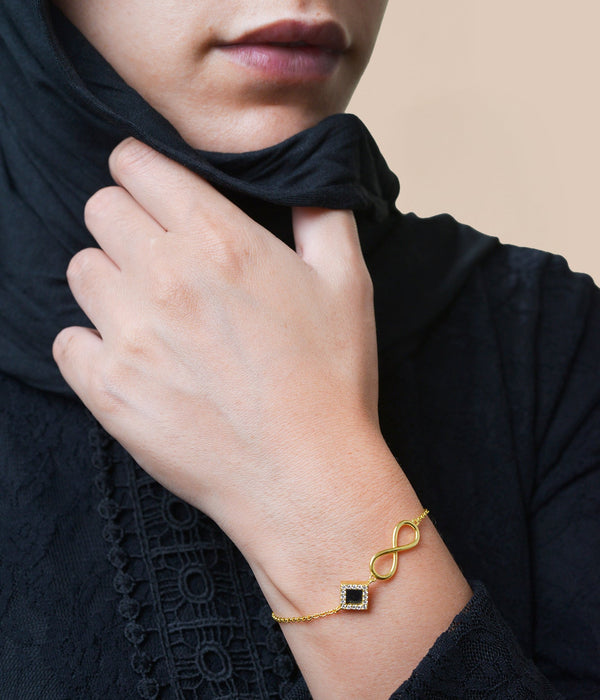 Model wearing a silver bracelet with an intertwined side design and a central square pendant that contains a black nano chip inscribed with the entire Quran, photographed against a beige-toned background.