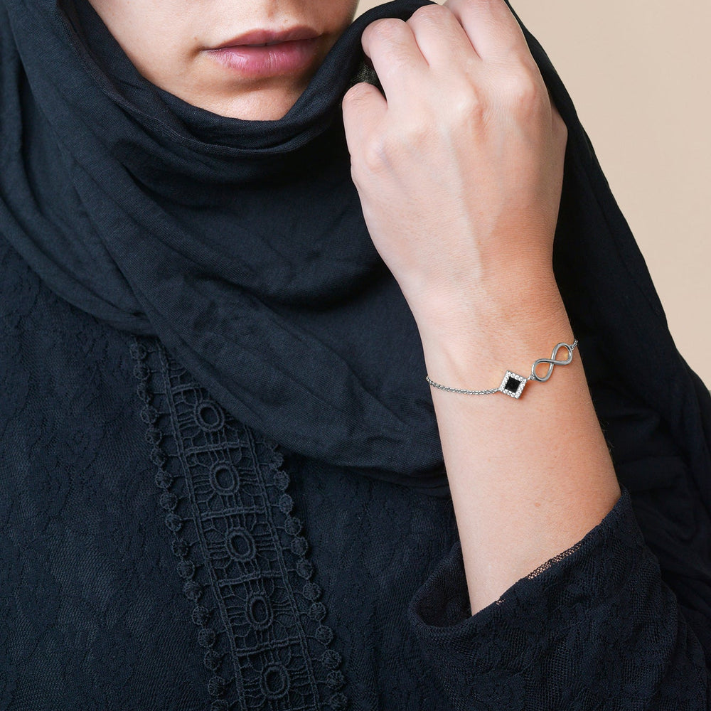 Silver bracelet with an intertwined side design and a central square pendant containing a black nano chip inscribed with the entire Quran, displayed on a white background.