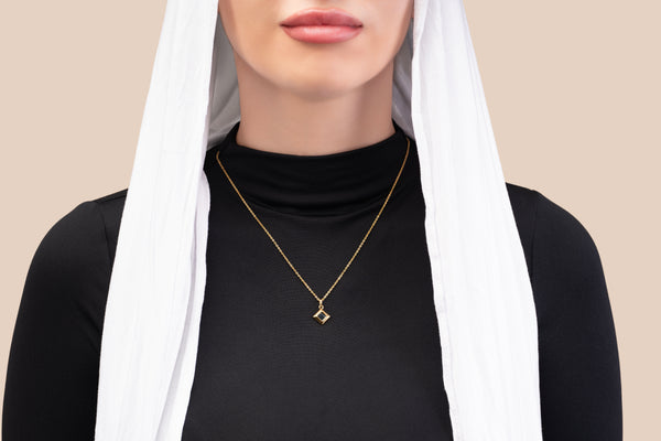 Model wearing a gold necklace with a square black nano-chip pendant that includes a Quran-inscribed nano chip, photographed against a soft beige-toned background.
