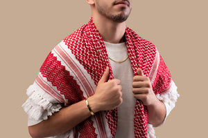 Male model wearing a gold Cuban chain necklace with a black nano chip near the clasp containing the full Quran, photographed against a beige-toned background.