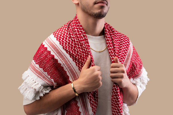 Male model wearing a gold Cuban chain necklace with a black nano chip near the clasp containing the full Quran, photographed against a beige-toned background.