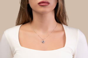 Model wearing a silver necklace with a round pendant that includes a black center stone and a nano chip micro-engraved with the entire Quran.