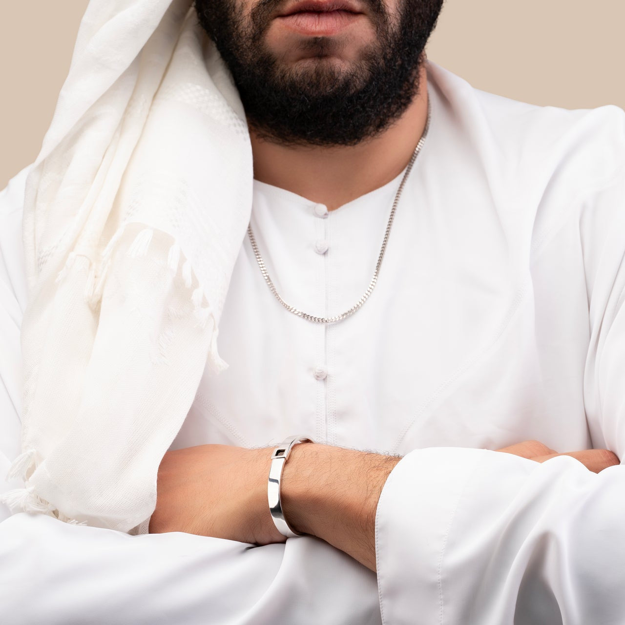 Male model wearing a silver cuff bracelet featuring a built-in black nano chip inscribed with the entire Quran, photographed against a beige-toned background.