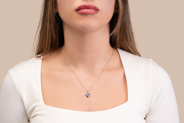 Model wearing a gold necklace with a square black nano-chip pendant that includes a Quran-inscribed nano chip, photographed against a soft beige-toned background.